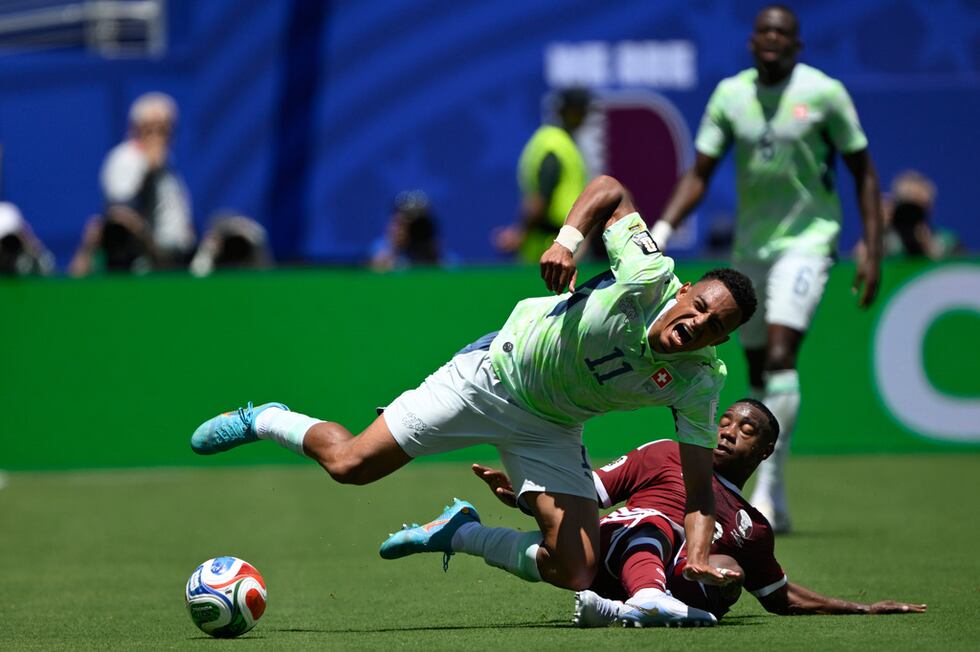 El suizo Dan Ndoye (izquierda) es derribado por el quatarí Assim Madibo durante el partido por...