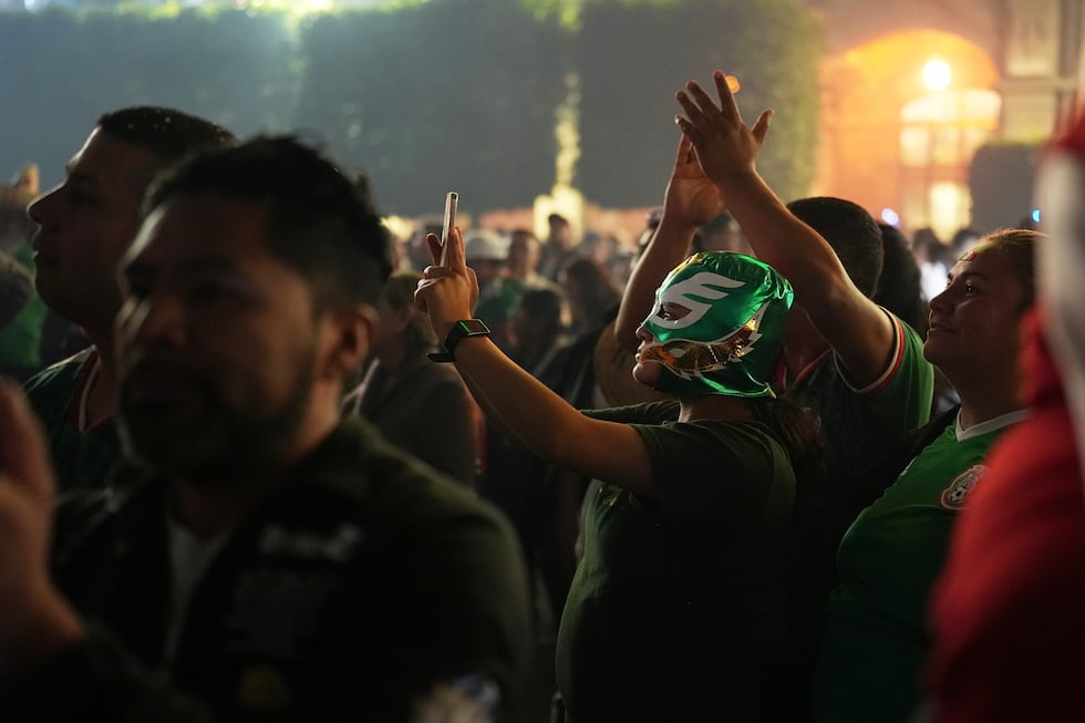 Gente observa a la presidenta de México, Claudia Sheinbaum, dar el grito anual desde el balcón...