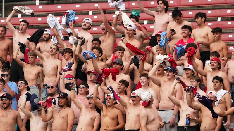 Fans cheer and wave their shirts during the first inning of a baseball game between St. Louis...