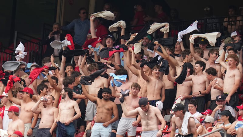Fans cheer and wave their shirts above their heads during the fourth inning of a baseball game...