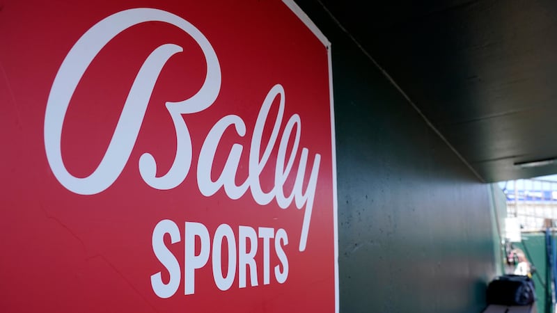 FILE - A Bally Sports logo is on a dugout wall during a spring training baseball game at Roger...