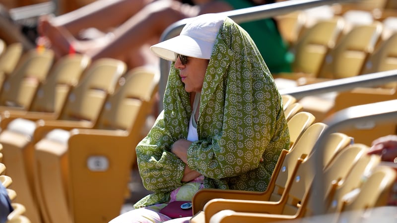 ARCHIVO – Una aficionada al béisbol se cubre del sol durante la cuarta entrada de un partido...