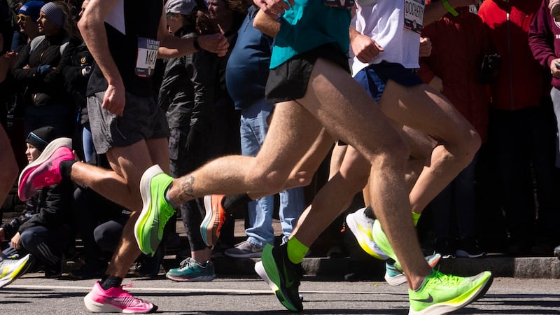 Runners wearing Nike ZoomX Vaporfly NEXT% shoes in green and pink compete in the U.S. Olympic...