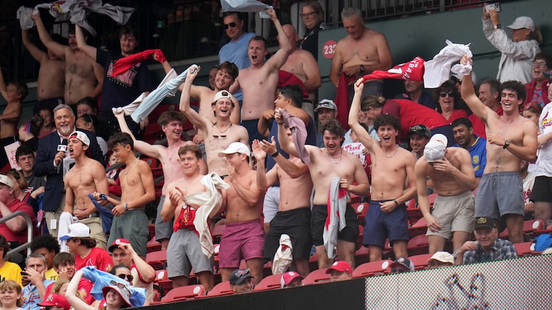 Fans cheer and wave their shirts above their heads during the fourth inning of a baseball game...