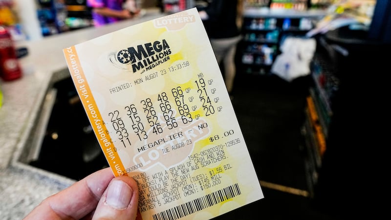 FILE - A Mega Millions ticket is seen as a person makes a purchase inside a convenience store,...